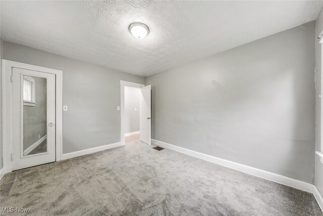 spare room featuring carpet and a textured ceiling