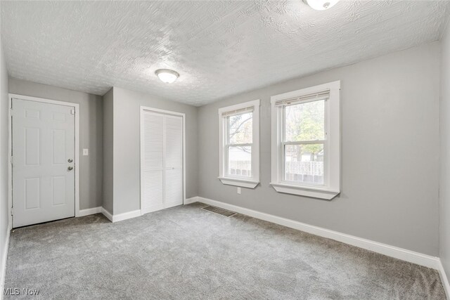 unfurnished bedroom with carpet floors, a textured ceiling, and a closet