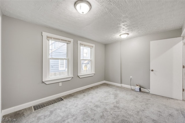 carpeted spare room with a textured ceiling