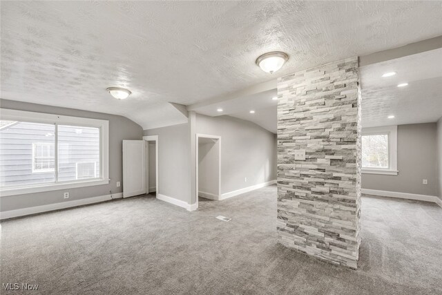 bonus room featuring a textured ceiling, light colored carpet, and lofted ceiling