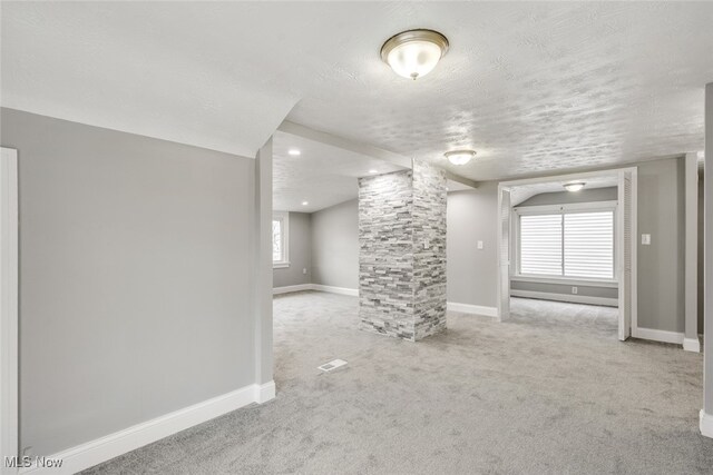 interior space with light carpet, a healthy amount of sunlight, and a textured ceiling