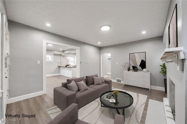 living area featuring arched walkways, visible vents, recessed lighting, wood finished floors, and baseboards