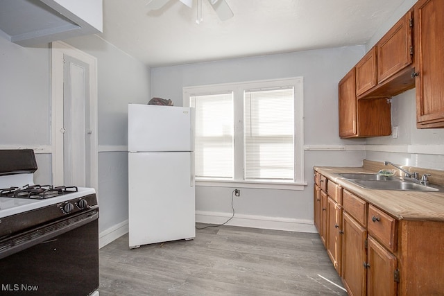 kitchen featuring ceiling fan, white appliances, sink, and light hardwood / wood-style flooring