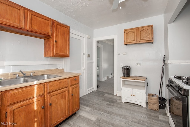 kitchen with ceiling fan, sink, white range with gas stovetop, and light wood-type flooring