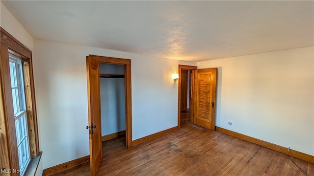 unfurnished bedroom featuring hardwood / wood-style floors, a textured ceiling, and a closet