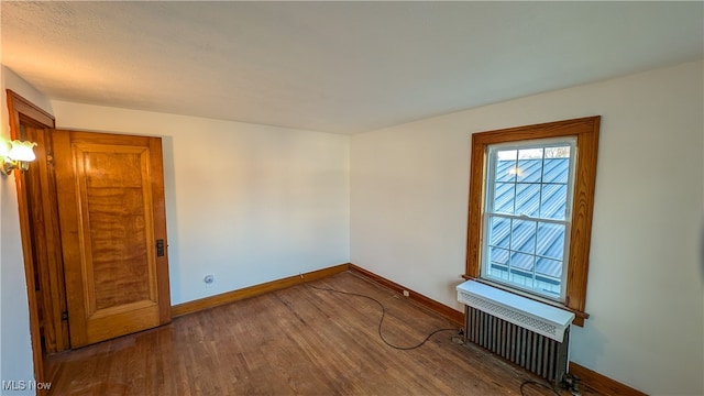 spare room with hardwood / wood-style floors and radiator heating unit