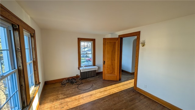 unfurnished room featuring dark hardwood / wood-style floors and radiator heating unit