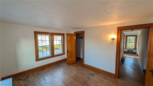 interior space with dark hardwood / wood-style flooring, a textured ceiling, and radiator