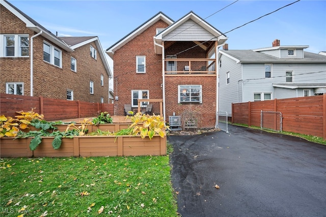 back of house with a yard and a balcony