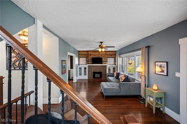 living room with wooden walls, dark hardwood / wood-style floors, ceiling fan, a textured ceiling, and a fireplace