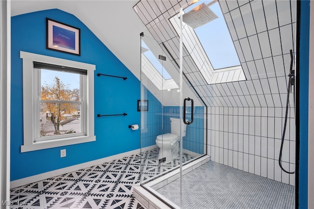 bathroom with tile patterned floors, vaulted ceiling with skylight, a shower with door, and toilet