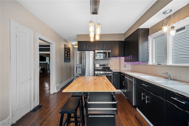 kitchen with appliances with stainless steel finishes, tasteful backsplash, pendant lighting, and sink