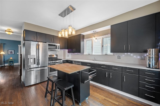 kitchen with decorative backsplash, appliances with stainless steel finishes, a breakfast bar, sink, and a kitchen island