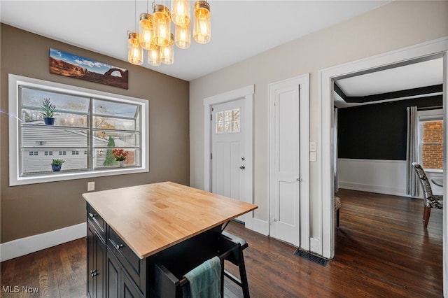 dining area featuring plenty of natural light, dark hardwood / wood-style floors, and an inviting chandelier