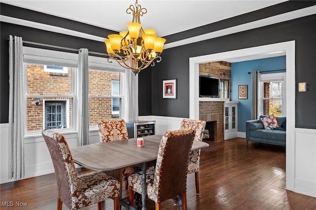 dining room featuring a chandelier, dark hardwood / wood-style flooring, and a brick fireplace