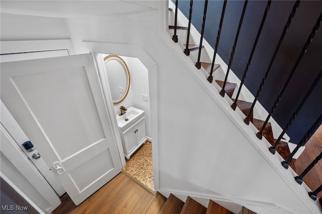 staircase with sink and hardwood / wood-style flooring