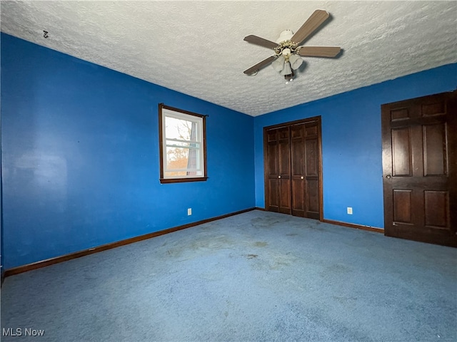 unfurnished bedroom featuring carpet flooring, ceiling fan, a textured ceiling, and a closet