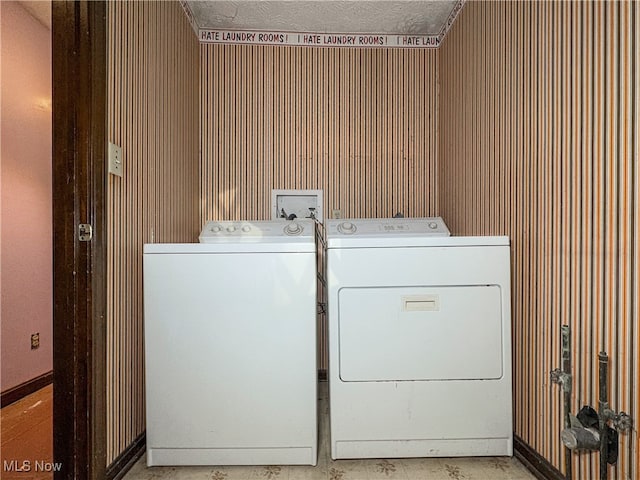 clothes washing area with separate washer and dryer and wood walls