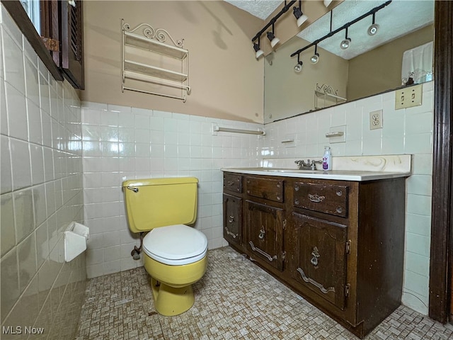 bathroom featuring tile patterned floors, vanity, tile walls, and toilet