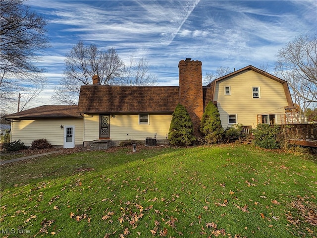 rear view of house featuring a lawn and central AC