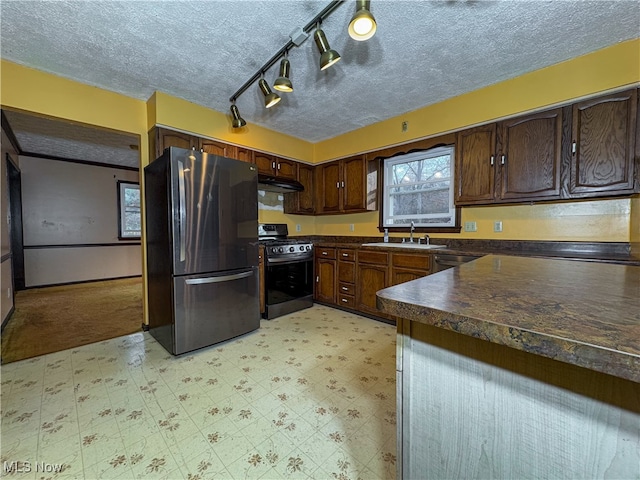 kitchen with a textured ceiling, dark brown cabinetry, stainless steel appliances, and rail lighting