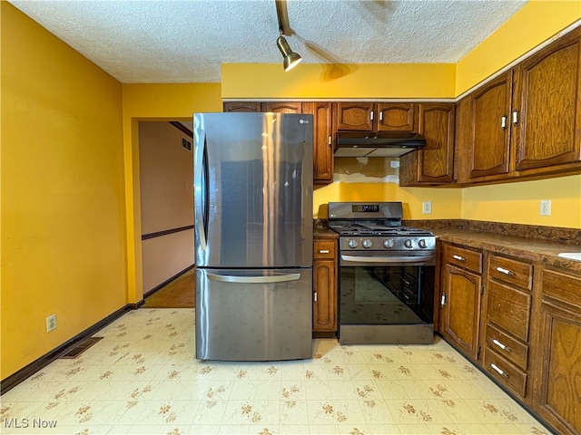 kitchen with a textured ceiling, stainless steel fridge, and black range with gas cooktop