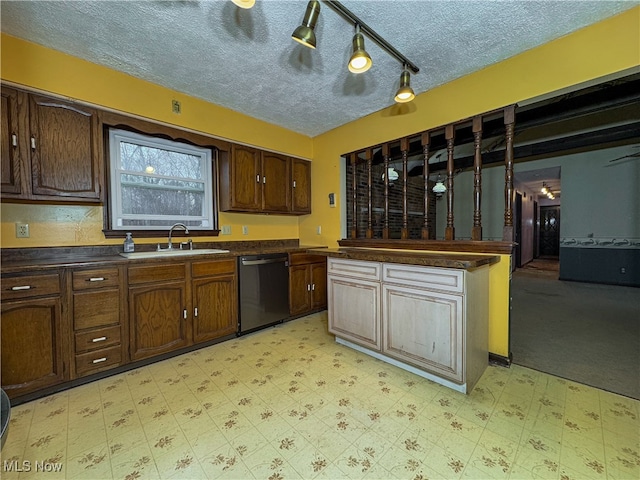 kitchen with dark brown cabinetry, dishwasher, sink, track lighting, and a textured ceiling