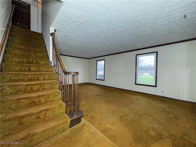 staircase with carpet flooring, a textured ceiling, and crown molding