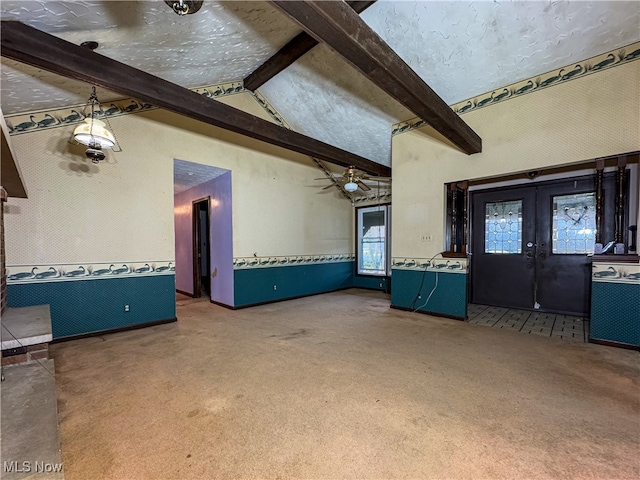 unfurnished living room with french doors, lofted ceiling with beams, carpet floors, and ceiling fan