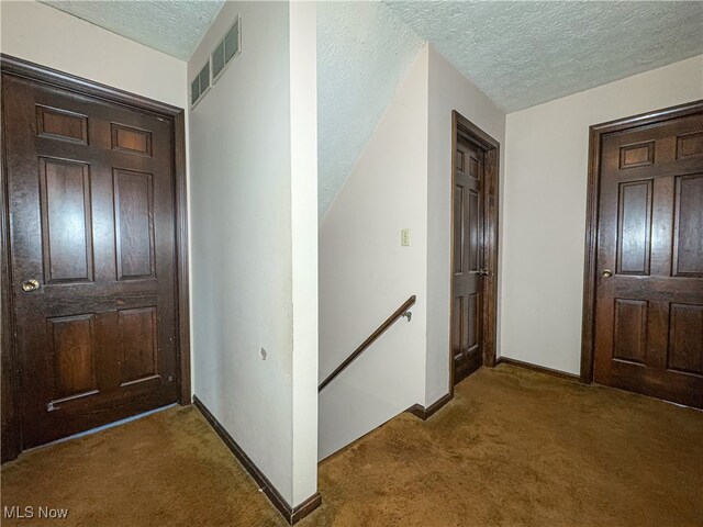 carpeted foyer entrance with a textured ceiling