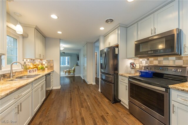 kitchen featuring sink, hanging light fixtures, stainless steel appliances, tasteful backsplash, and dark hardwood / wood-style flooring