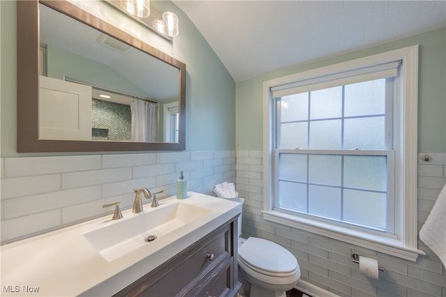 bathroom with vanity, toilet, lofted ceiling, and tile walls