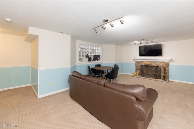 carpeted living room featuring a stone fireplace and a textured ceiling