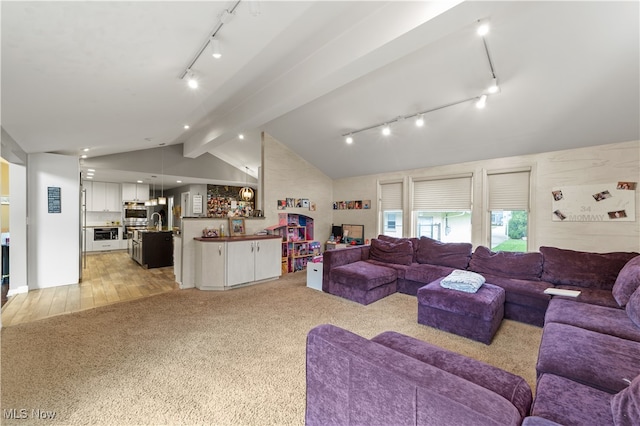 living room with light wood-type flooring, lofted ceiling with beams, and sink