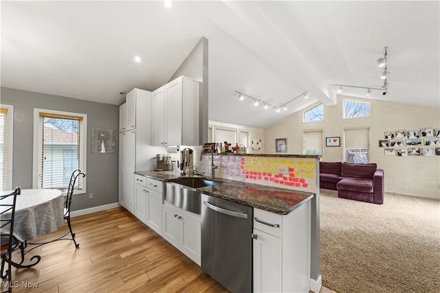 kitchen with white cabinetry, dishwasher, lofted ceiling with beams, dark stone countertops, and light hardwood / wood-style floors