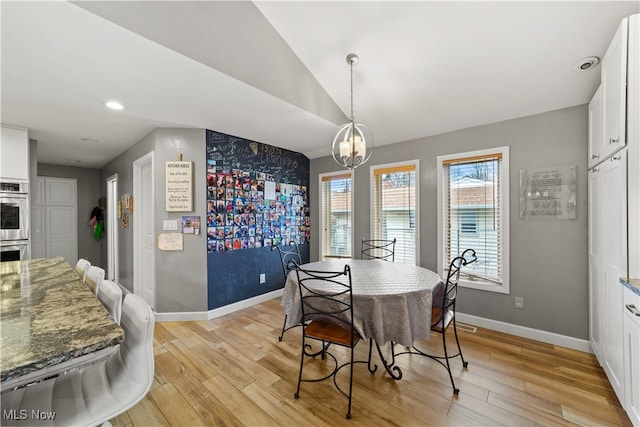 dining space featuring vaulted ceiling, light hardwood / wood-style flooring, and a notable chandelier