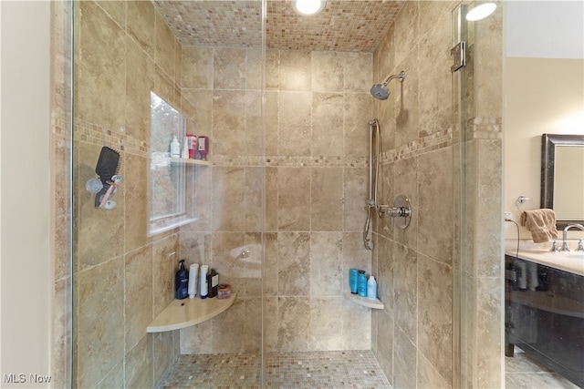 bathroom with a tile shower and vanity