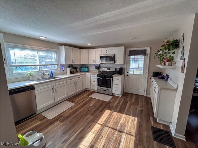 kitchen featuring a textured ceiling, stainless steel appliances, sink, dark hardwood / wood-style floors, and white cabinetry