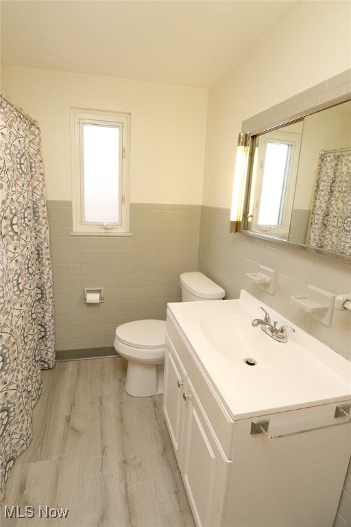 bathroom with vanity, hardwood / wood-style flooring, plenty of natural light, and tile walls