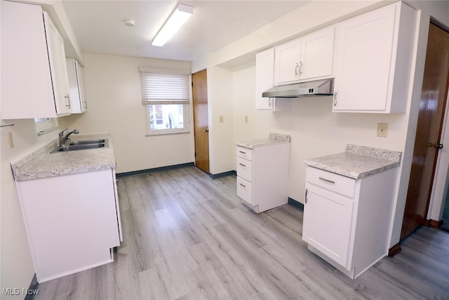 kitchen featuring white cabinets, light hardwood / wood-style floors, and sink