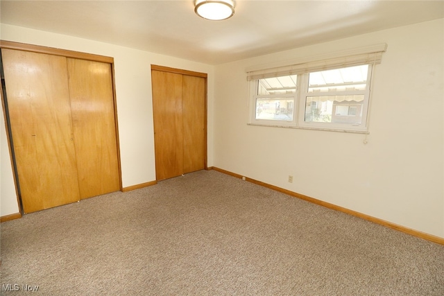 unfurnished bedroom with carpet floors and two closets