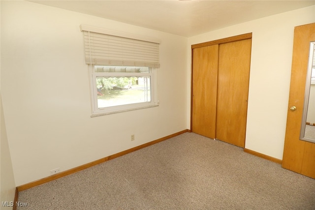 unfurnished bedroom with a closet and light colored carpet