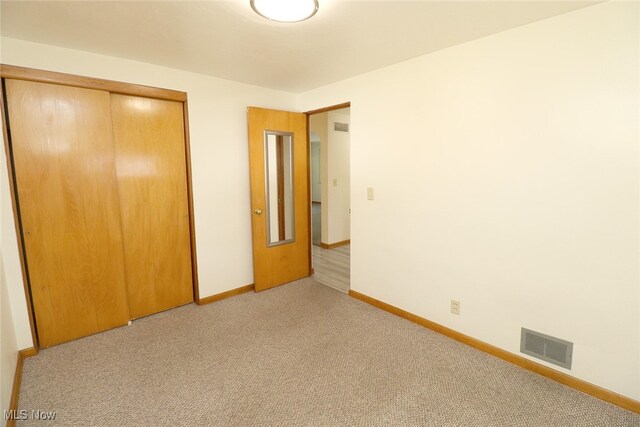 unfurnished bedroom with light colored carpet and a closet