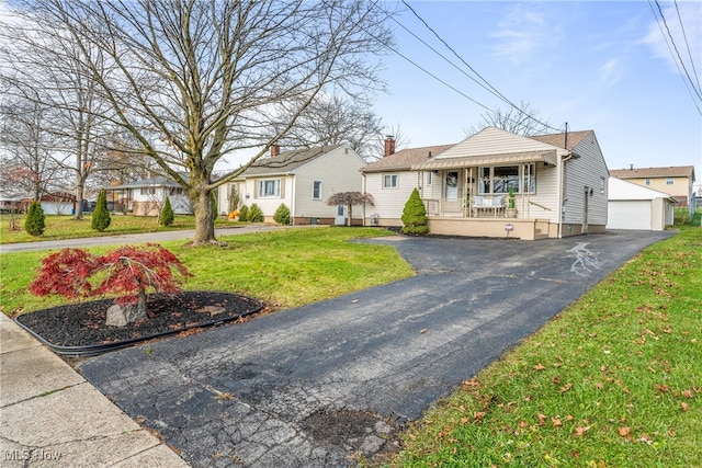 view of front of property featuring an outbuilding, a front lawn, a porch, and a garage