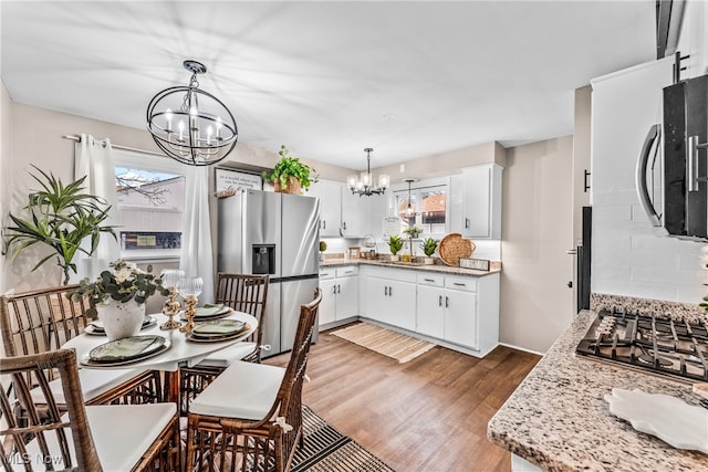 kitchen with hardwood / wood-style floors, a healthy amount of sunlight, white cabinetry, and appliances with stainless steel finishes