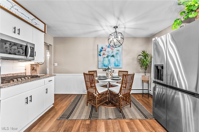 dining area featuring a chandelier, hardwood / wood-style floors, and a baseboard heating unit