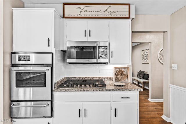 kitchen featuring stainless steel appliances, white cabinetry, dark hardwood / wood-style floors, and dark stone counters