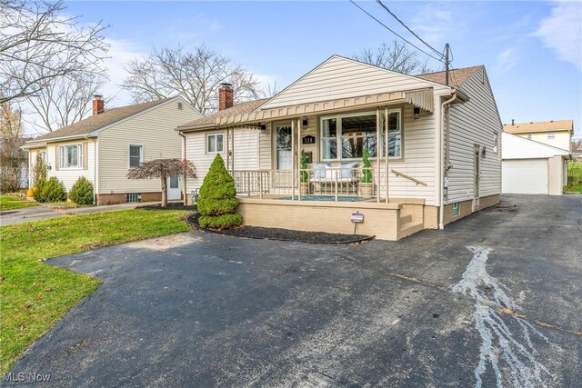 bungalow-style house with a porch, a garage, an outdoor structure, and a front yard