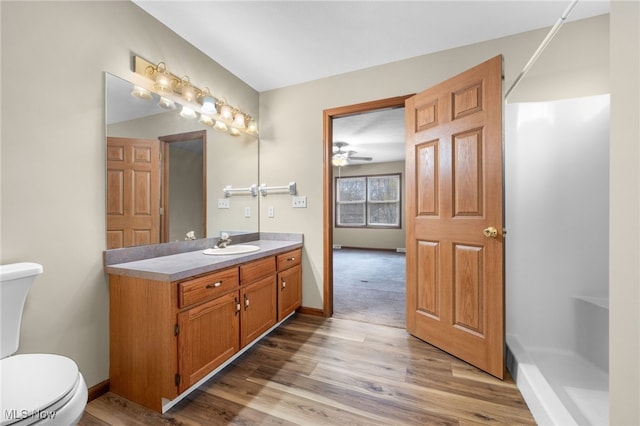 bathroom featuring hardwood / wood-style floors, vanity, ceiling fan, toilet, and walk in shower