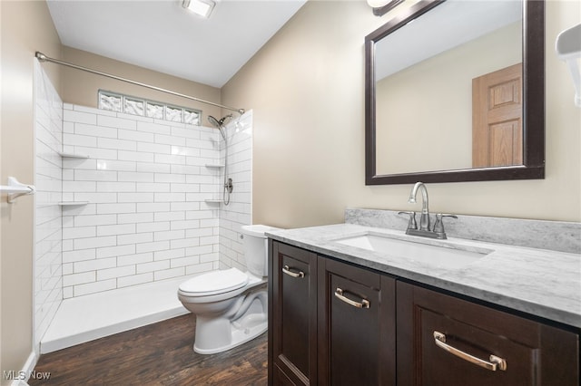 bathroom with tiled shower, hardwood / wood-style floors, vanity, and toilet